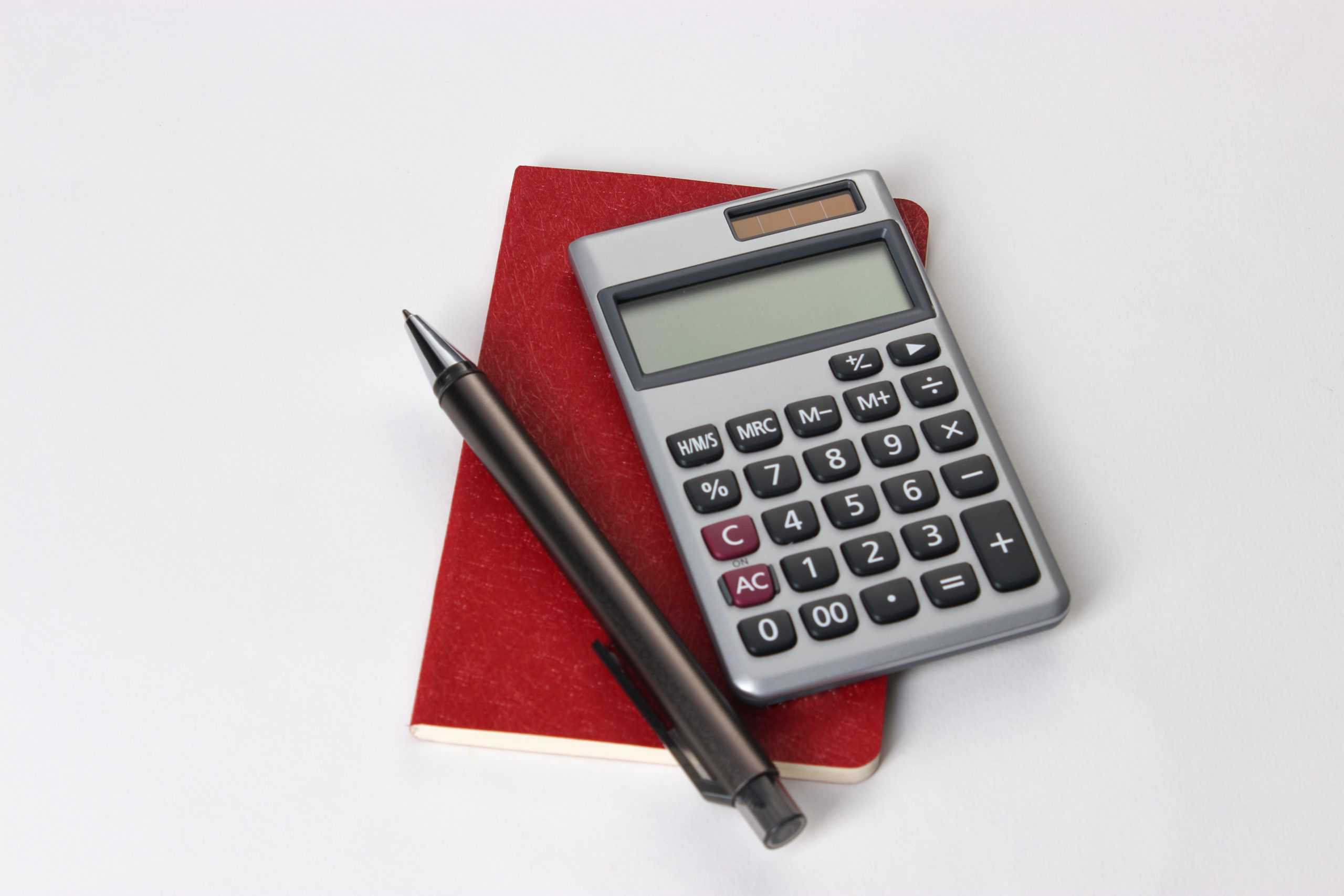 Kalkulator, en penn og en rød skrivebok
