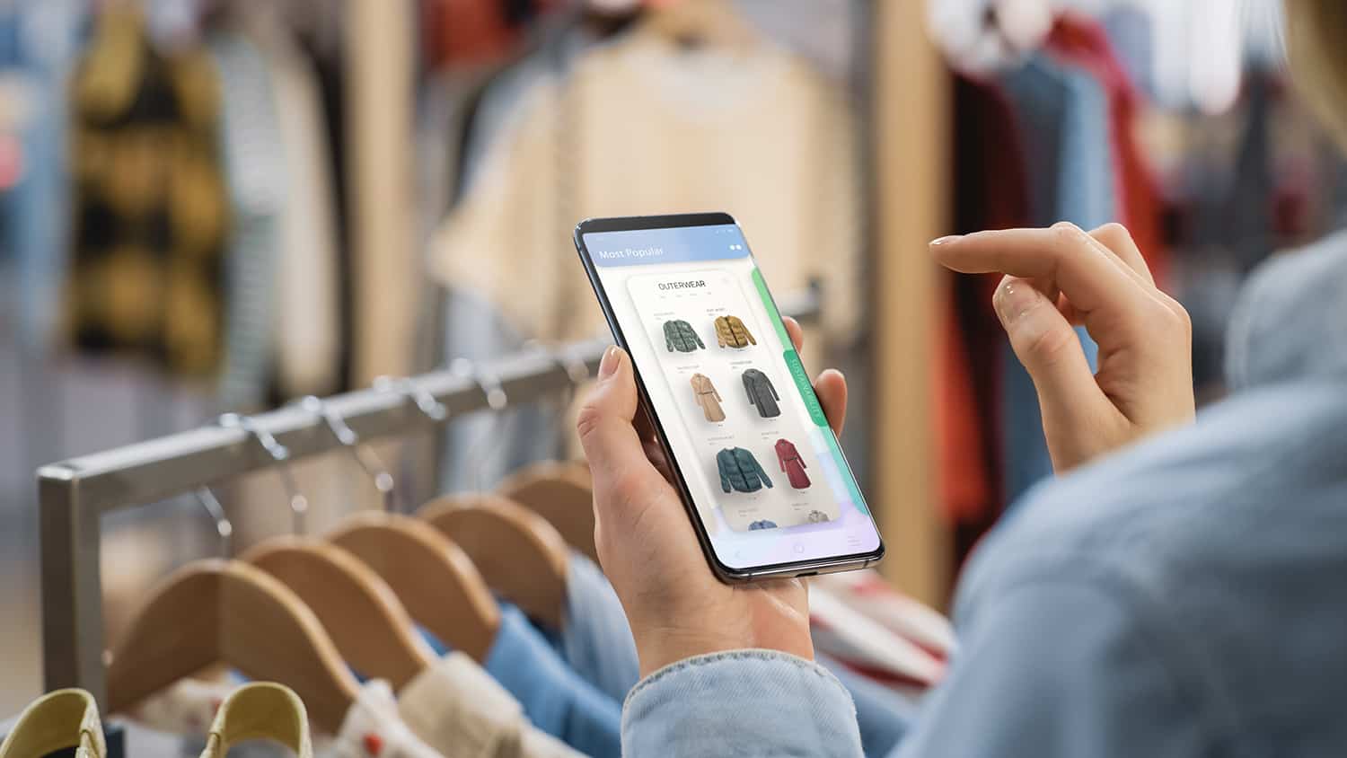 En jente bruker mobilen til å se på klær hun vurderer å kjøpe.