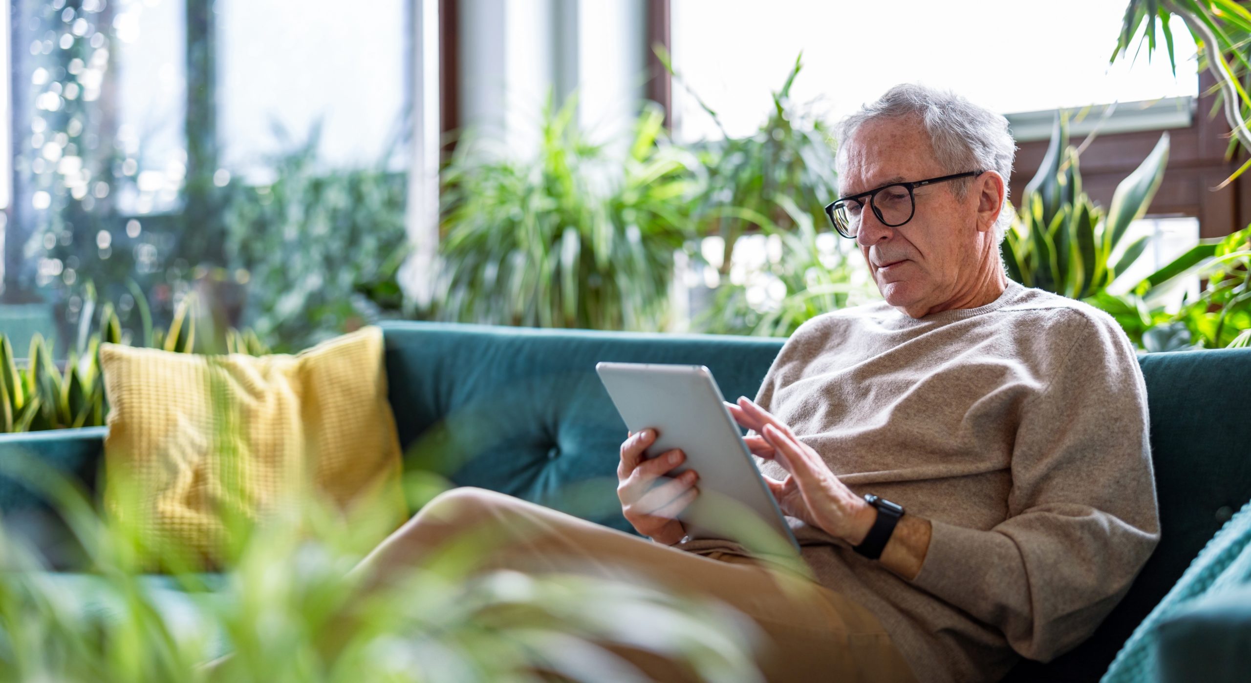 Senior,Man,Using,Digital,Tablet,While,Sitting,On,Sofa,In